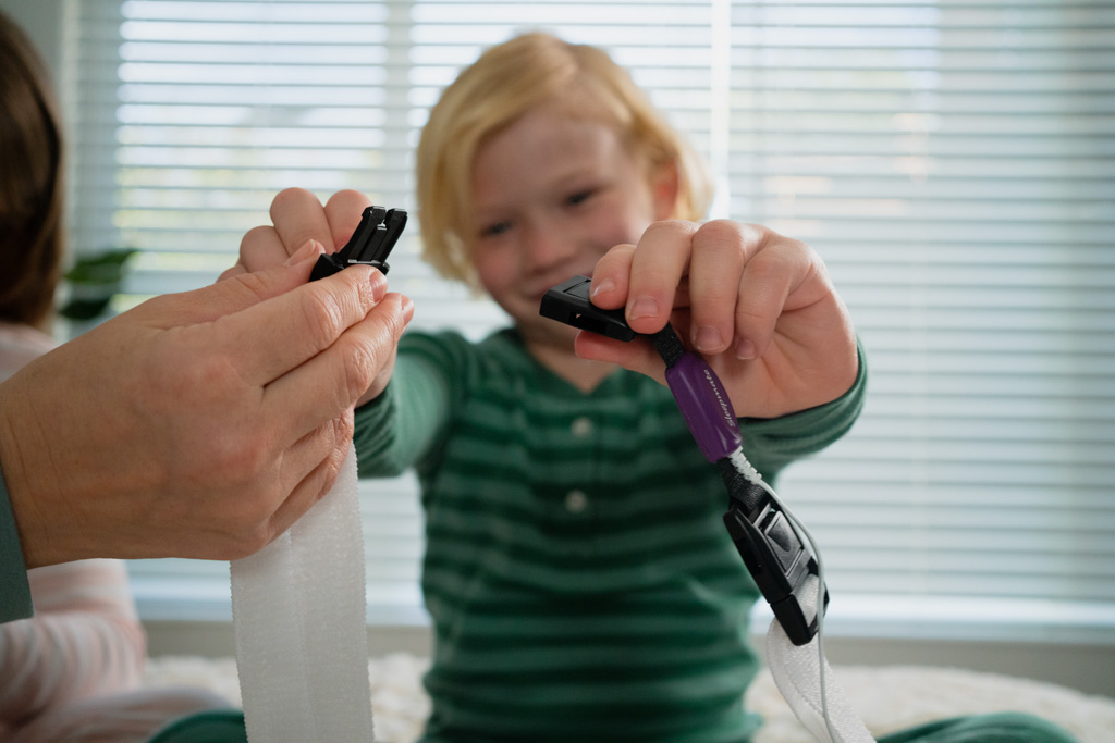 A parent helps her child apply the respiratory effort sensor and chest belt