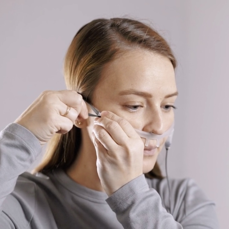 An adult wearing a nasal cannula and airflow sensor as part of a Snap Diagnostics' home sleep apnea test